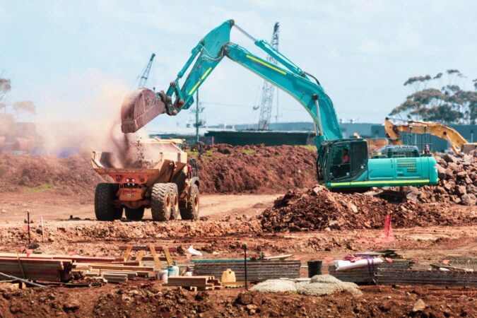 digger dropping rubble into truck.