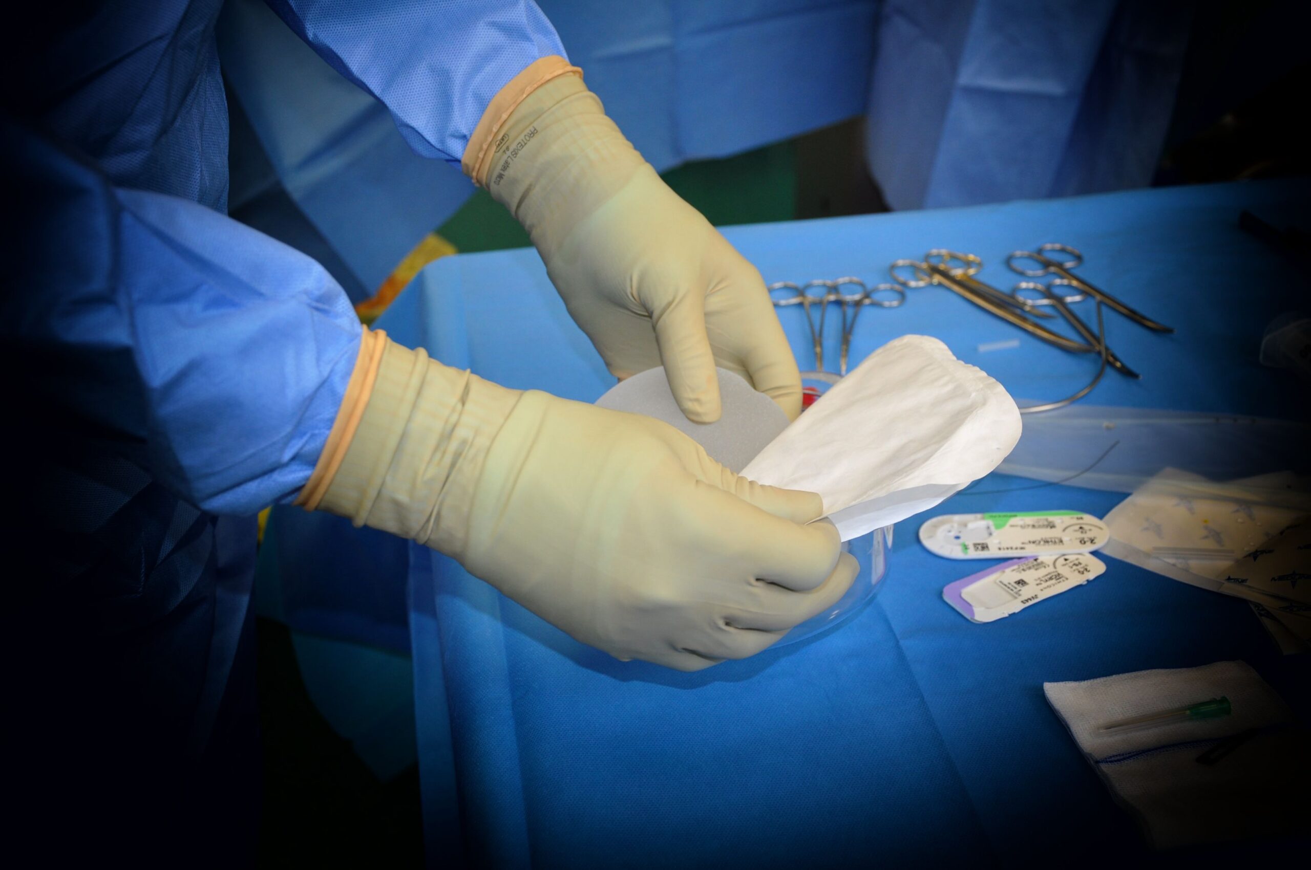 doctor's hands in gloves holding mask.