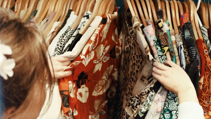 woman looking through clothes in charity shop.