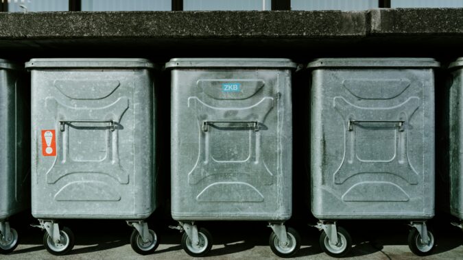 three metal dumpsters outside in a row.